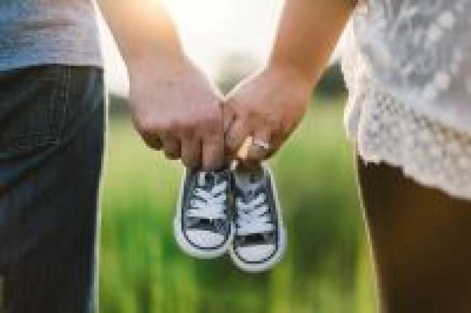 Twee handen houden samen een paar kleine sneakers vast