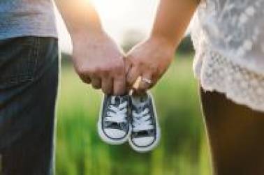 Twee handen houden samen een paar kleine sneakers vast
