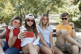 Decoratieve afbeelding: 4 jongeren zitten op een bankje en maken een selfie