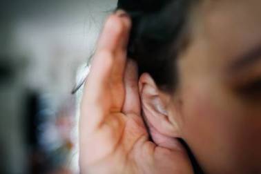 Decoratieve afbeelding: Een foto van iemand die zijn of haar hand achter het oor houdt.