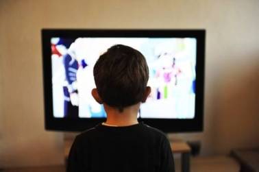 Decoratieve afbeelding: Een foto van een jongen dat naar een televisiescherm kijkt.