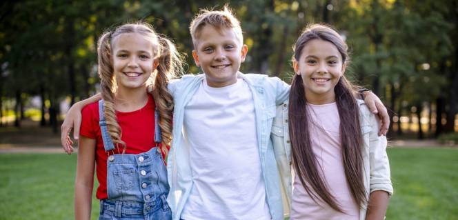 jongen staat tussen 2 meisjes in, met armen om hen heen